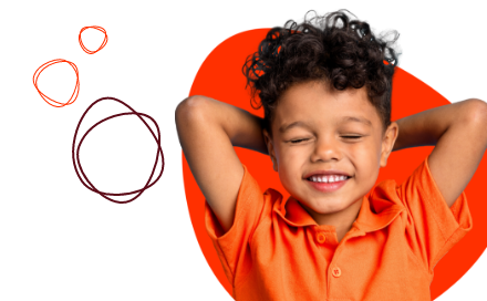 A young child in an orange shirt smiles with their eyes closed and arms behind their head against a background with colorful circular designs.