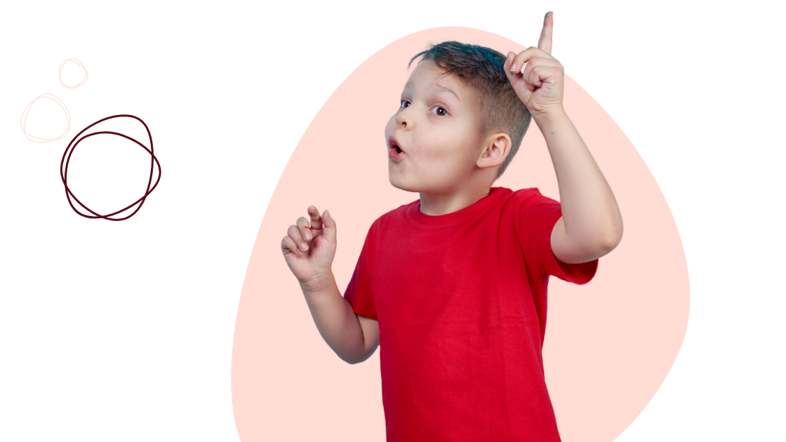 A young boy in a red shirt raises his index finger, appearing to have an idea, against a light pink background with simple, abstract shapes.