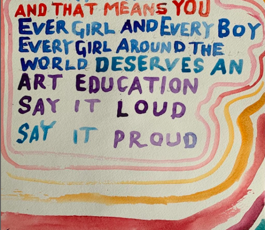 A colorful handwritten sign reads, "Every child and that means you, every girl and every boy, every girl around the world deserves an art education. Say it loud, say it proud.