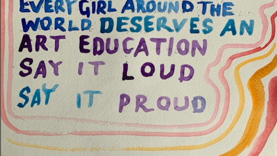 A colorful handwritten sign reads, "Every child and that means you, every girl and every boy, every girl around the world deserves an art education. Say it loud, say it proud.